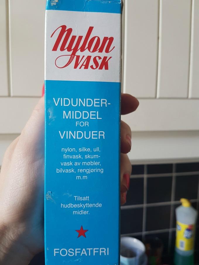 Bilde av en hånd som holder en blå eske med Nylonvask foran kjøkkenskap.