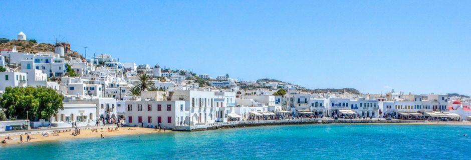 Nå lanseres det også reiser til Mykonos i Apollo sine kombinasjonreiser til hellas. Her er en strand, strandpromenade og havn avbildet på den vakre øya.