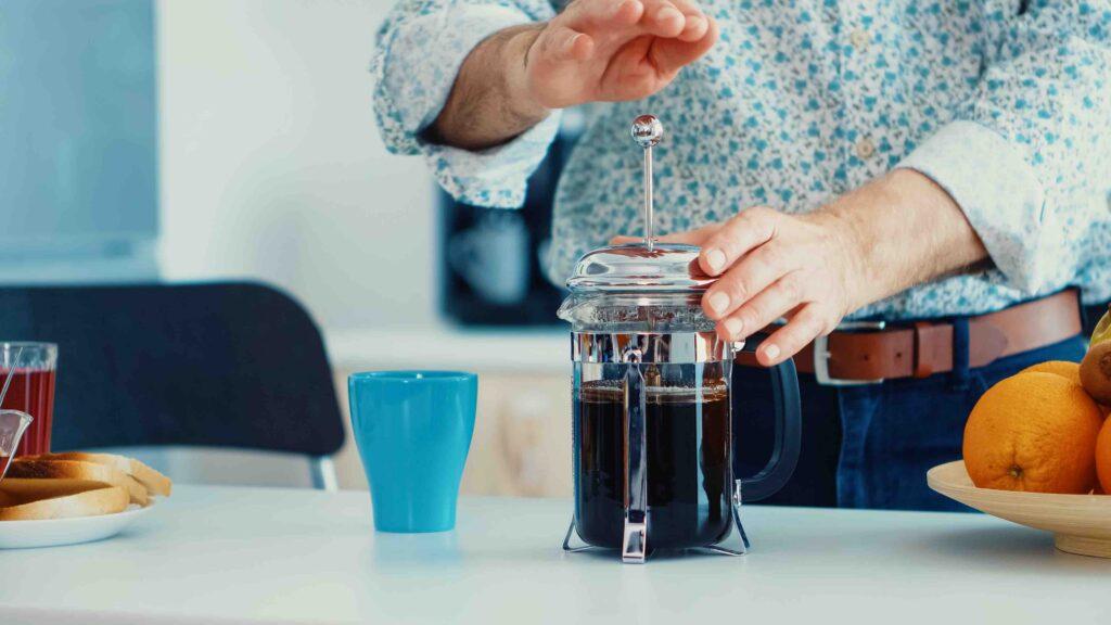 eldre mann som lager dresskannekaffe til frokost. presskanne eller French press som det også ofte kalles smaker godt og gjør seg godt på frokostbordet