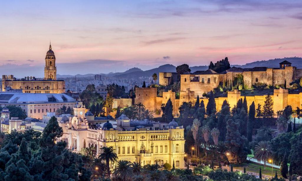 malaga på kveldstid viser opplyste slott og gamle bygninger