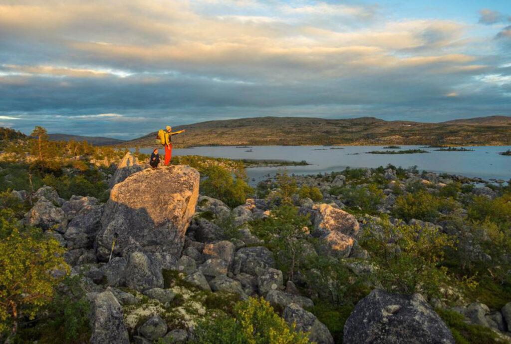 Personer som står i Femundmarka, på toppen av en stein og peker ut over innsjø i Norge. En av våre anbefalte fjellturer i Norge.