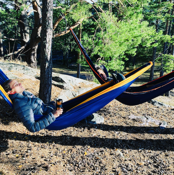 To damer i hver sin hengekøye på tur i skogen.