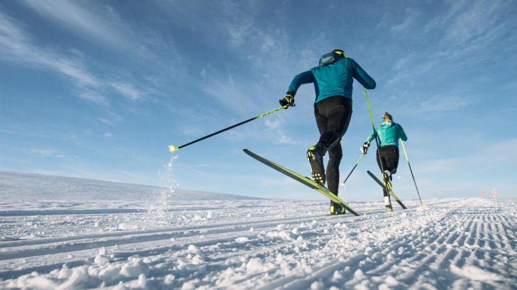 Bilde av to personer i skiløyper på felleski med blå himmel, og mye snø