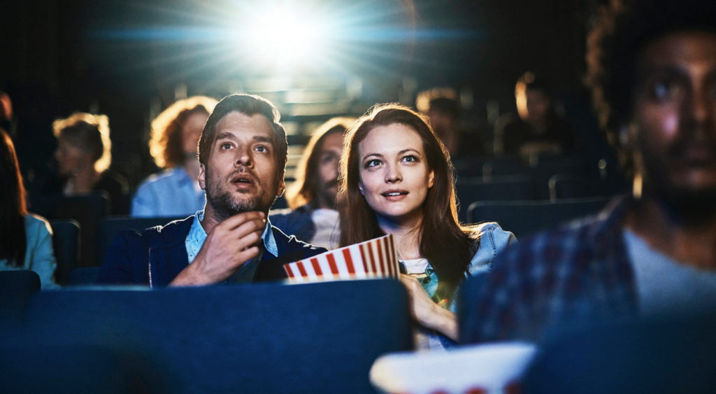 bilde av to mennesker på valentinsdagsdate på kino. De ser på en spennende film med popcorn og brus