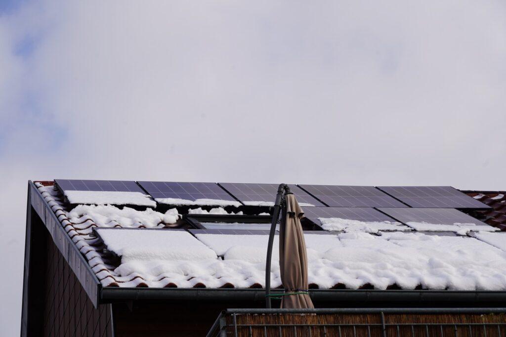 Bilde av et hustak med solcellepanel dekket av snø. Vi svarer på alt du trenger å vite, som hvordan montere solcellepanel? Er solcellepanel lønnsomt? og, hvorfor velge solcellepanel?