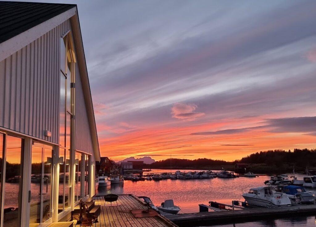 Bilde av Kjerringøy Bryggehotell i vakker solnedgang. Her finner du overnatting på Kjerringøy, blant annet Kjerringøy Bryggehotell som har blitt brukt i innspillingen til Hver gang vi møtes. Du finner også Kjerringøy rorbusenter og Kjerringøy Camping.