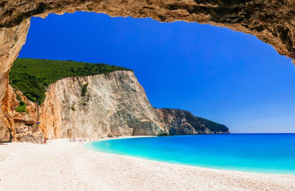 Bilde av en hvit strand på Lefkas i Hellas som er omringet av klipper og knallblått hav. Vi hjelper deg med å planlegge Hellas-ferien ved å svare på «Hvor i Hellas skal man reise?». Vi har snakket med reiseekspert Odd Roar Lange som kommer med tips som Syros, Alonissos, Karpathos, Lefkas, Thassos, Preveza, Ioannina, Parga, Kreta, Samos, Santorini, Rhodos og Kos.