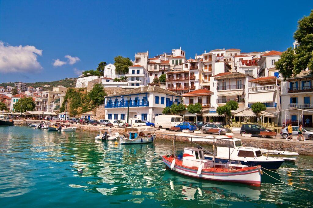 Bilde av Skopelos Town, eller Chora som den også heter. Her ser du knallblått hav på den ene siden og hvite hus med røde tak på den andre siden. Vi hjelper deg med å finne billige reiser til Skopelos som er den greske øya hvor «Mamma Mia» ble spilt inn. Vi gir deg også fem tips til hva du må se på øya som ligger i Hellas, som blant annet Agios Ioannis og Cape Amarandos.