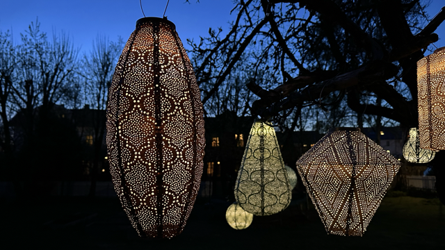 Bilde av Lumiz solcelle-lanterner i en hage på kveldstid.