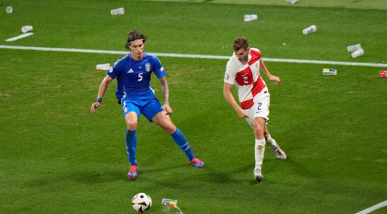 Croatia's Martin Erlic, right, and Italy's Riccardo Calafiori challenge for the ball as plastic cups and glasses litter the pitch during the Group B match between Croatia and Italy at the Euro 2024 soccer tournament in Leipzig, Germany, Monday, June 24, 2024