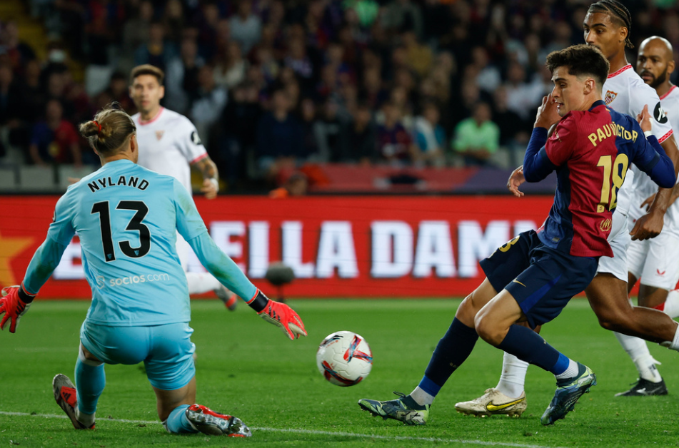 Sevilla's goalkeeper Orjan Nyland, left, makes a save in front of Barcelona's Pau Victor during a Spanish La Liga soccer match between Barcelona and Sevilla at the Olimpic Lluis Companys stadium in Barcelona, Spain, Sunday, Oct. 20, 2024