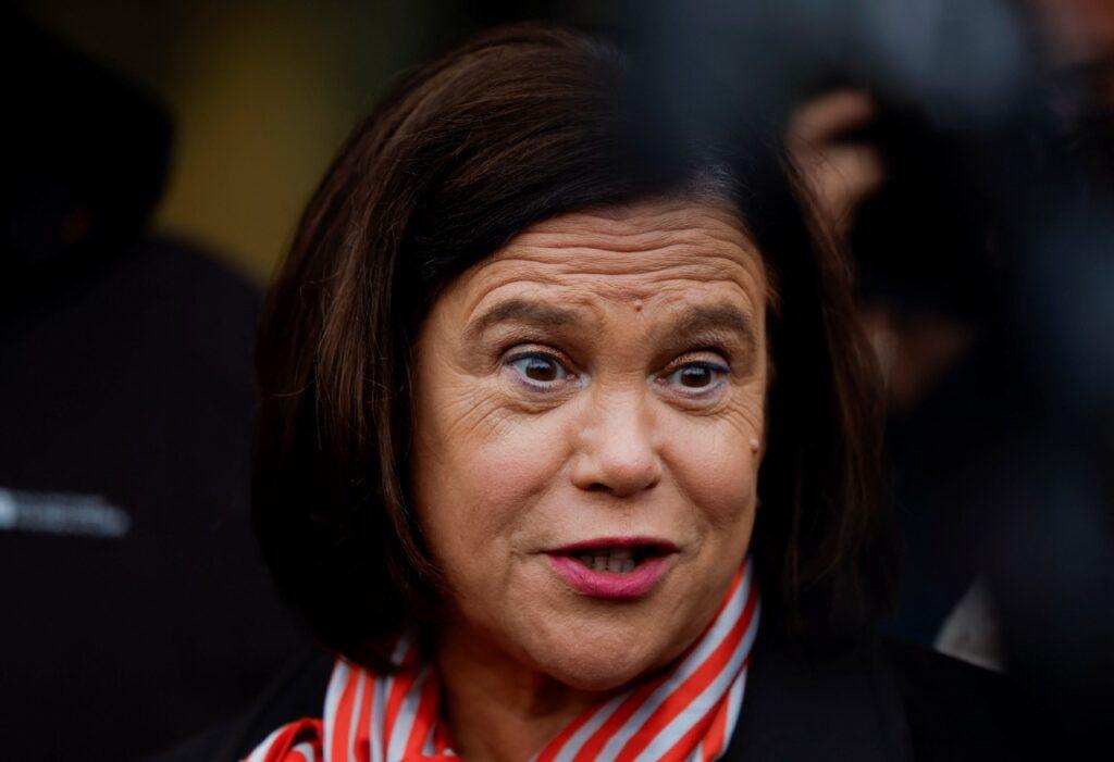 Mary Lou McDonald, leder av Sinn Féin, snakker med media under valgdagen i Irland, ikledd en stripete skjerf og sort jakke.