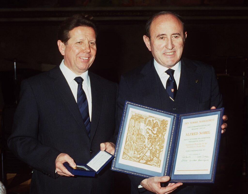 Bildet viser Jevgenij Tsjasov og Bernard Lown som mottar Nobels fredspris for 1985 på vegne av organisasjonen Leger mot Atomvåpen. De står sammen i formelle dresser; Lown holder fredsprisdiplomet som ble utdelt i Oslo Rådhus. Bildet representerer Nobels fredspris og innsatsen mot atomkrig.