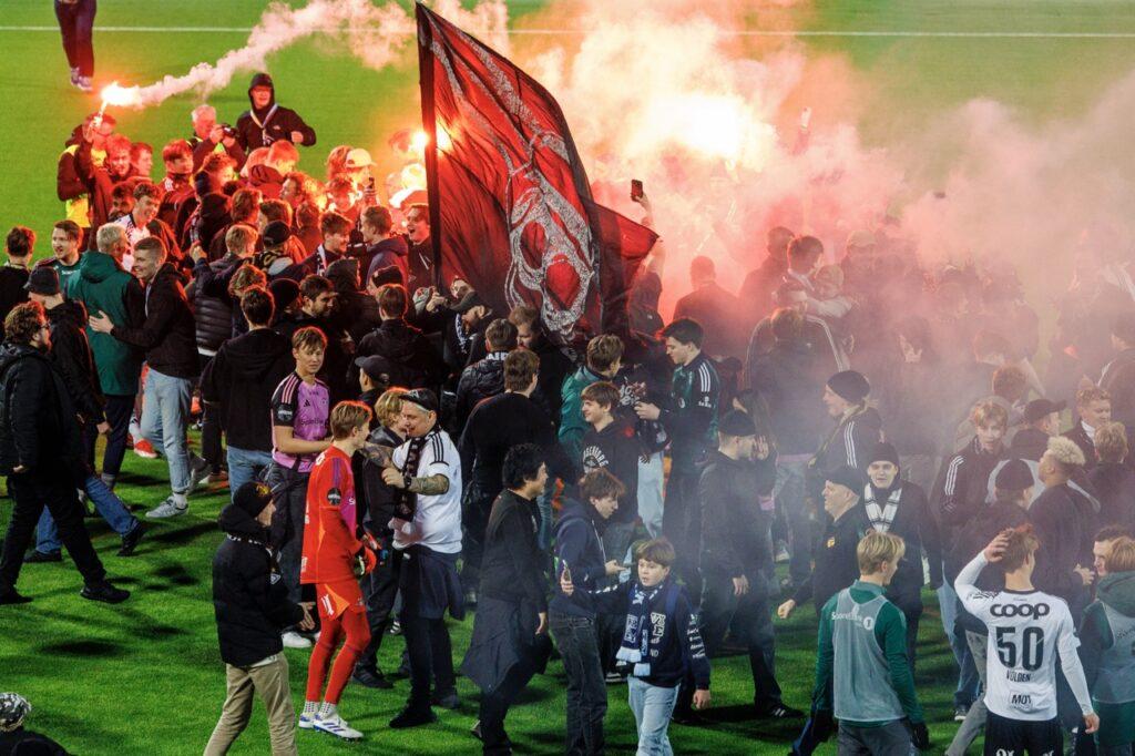 En gruppe Rosenborg-supportere stormer banen, noen med fakler, etter eliteseriekampen mellom Kristiansund og Rosenborg på Nordmøre Stadion.