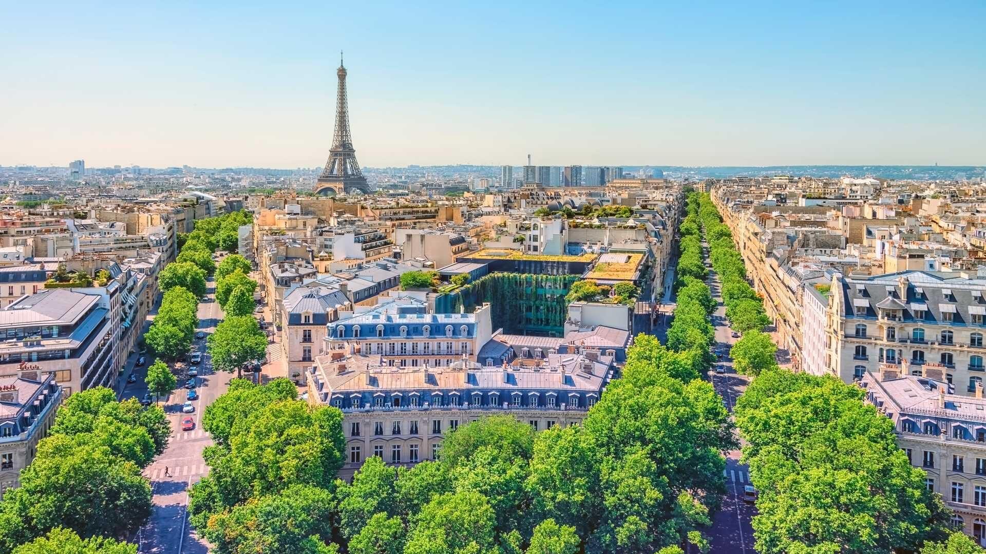 På bilde ser du oversiktsbilde av Paris, Frankrike. På bilde ser du byens gater med grønne trær og Eiffeltårnet i bakgrunn