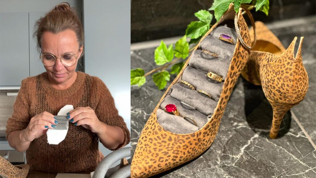 Bildet viser Lise Wolden i en brun strikkegenser og runde briller mens hun arbeider med et DIY-prosjekt. Hun lager en smykkeholder ved å bruke en leopardmønstret høyhælssko og grått polstret stoff. Til høyre ser vi den ferdige smykkeholderen, hvor skoen er fylt med ruller av stoff for å holde ringer og smykker. En grønn plante tilfører en dekorativ detalj, og bakgrunnen består av en mørk marmorovertflate.