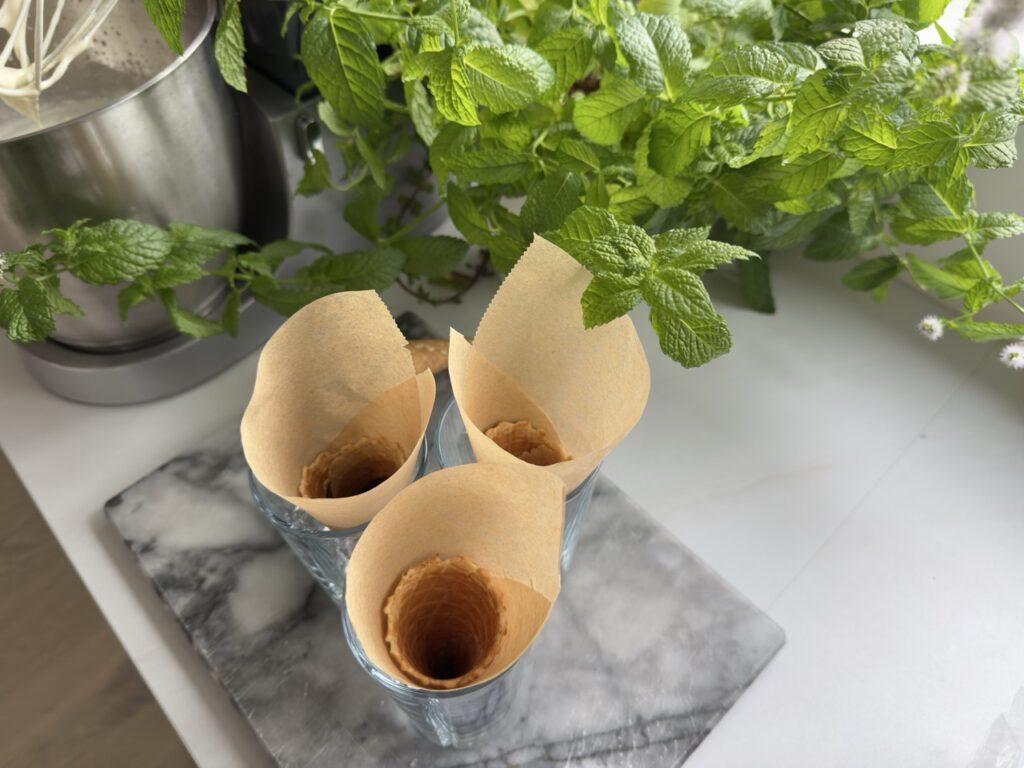 Hjemmelaget kroneis starter med enkle forberedelser: vaffelkjeks plassert i glass og foret med bakepapir, klare til å fylles med iskrem og smakslag.