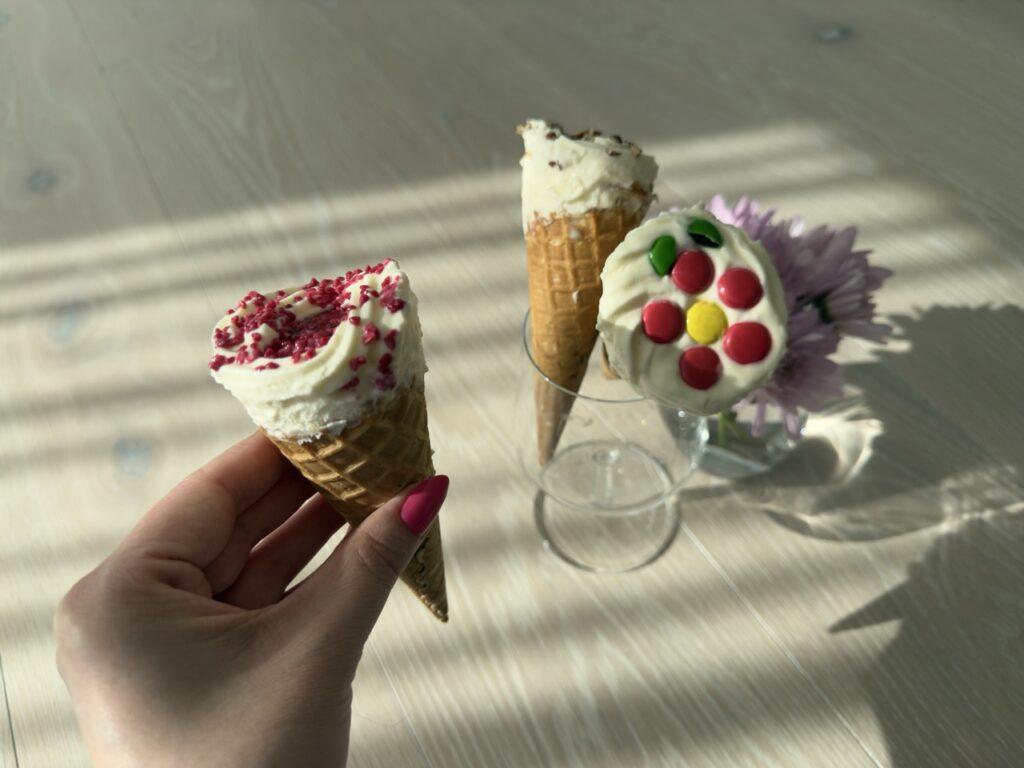 Et nærbilde viser detaljene i de tre ulike kroneisene: Non-stop dekorert som blomst, bringebærstrø og en variant med hakkede pekannøtter og karamellsaus.