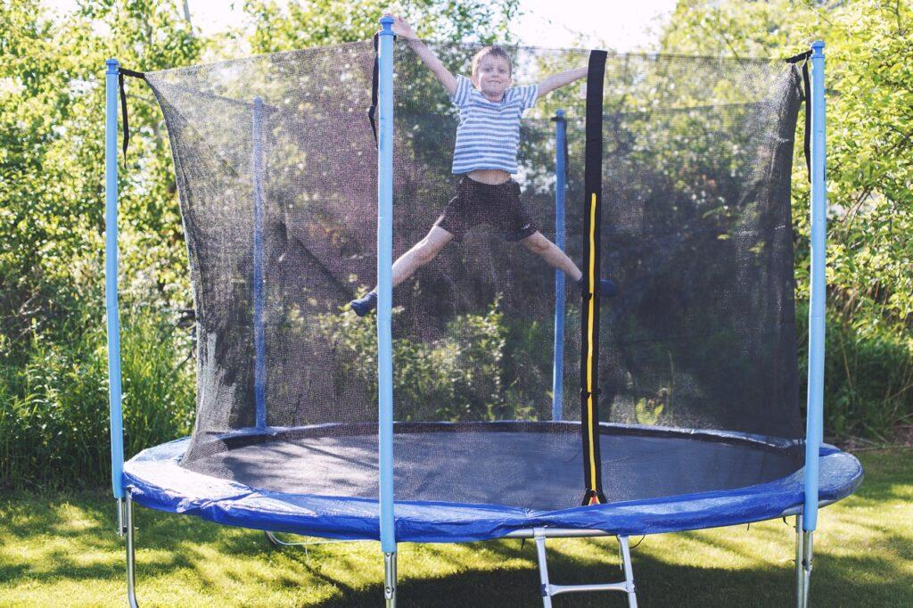 gutt som hopper på trampoline en trampoline i hage. Hvilken trampoline som er best i test får du svaret på her.