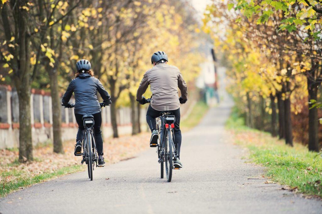 To personer som sykler gjennom park på elsykkel, vi viser deg hvordan du velger riktig elsykkel.
