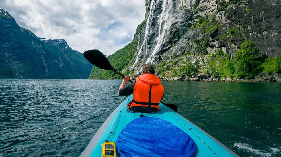 Bilde av person på packraft på fjord mellom fjell.