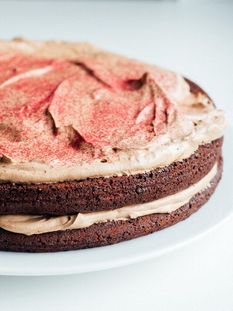 Vi deler oppskrift på avbildet saftig, vegansk sjokoladekake. Her på nærbilde med glasur og rosa dryss.