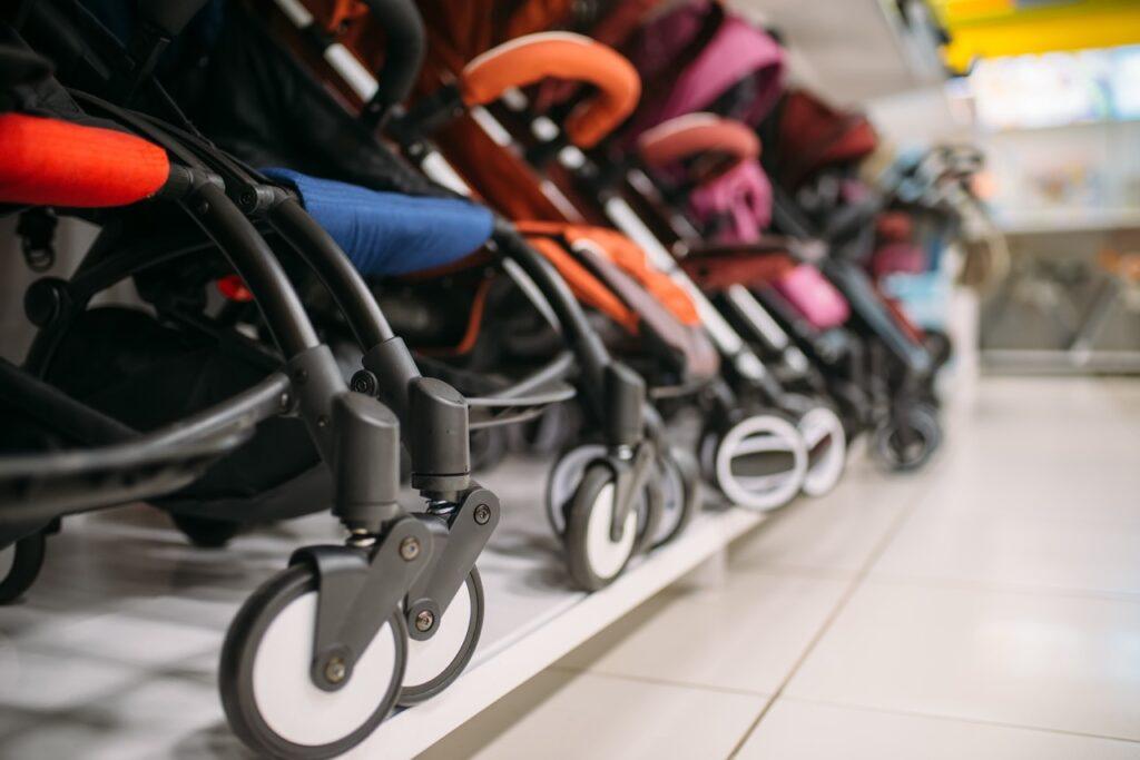 Bilde av flere fargerike barnevogner i blå, oransje, rosa og rød på rekke og rad i en barnebutikk. Merker som Stokke, Simo, Thule og Cybex er blandt barnevognene det søkes mest etter i år, men er de best i test? Vi avslører hvilke vogner som er best i 2023!