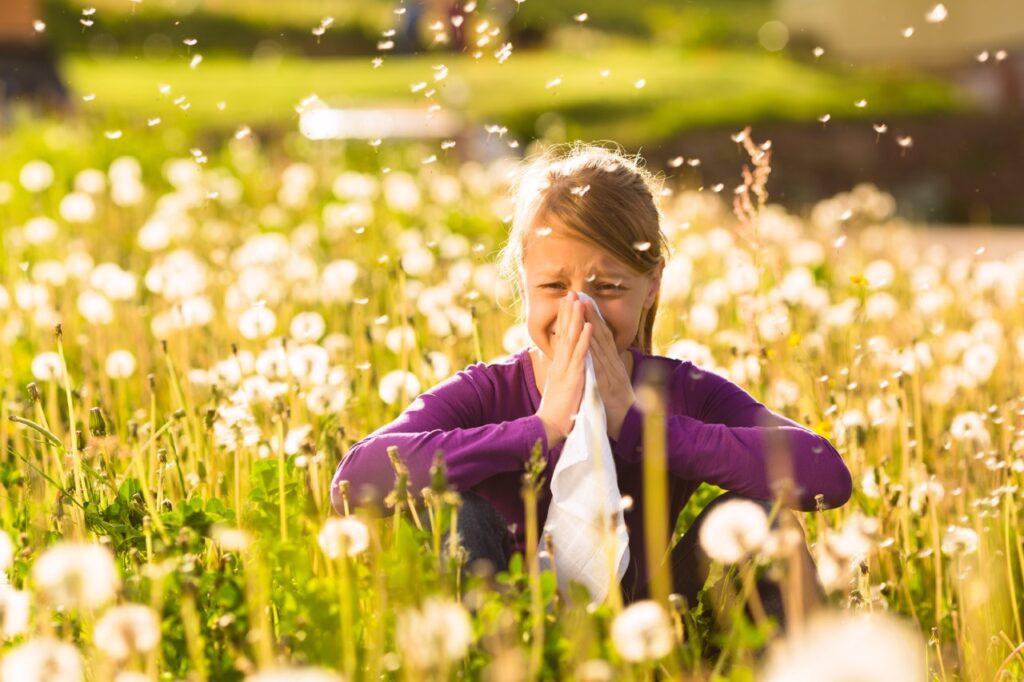 Luftrenser test: En jente sitter i en eng og snyter seg i nesa.