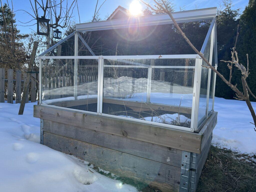 Bilde av drivhus på pallekarmer. Fortsatt snø rundt. Drivhus på pallekarmer er perfekt for deg som har begrenset plass i hagen.
