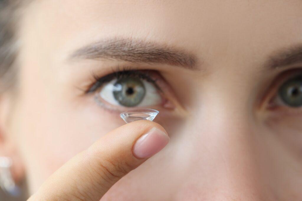 Nærbilde av øynene til en person som holder en kontaktlinse på fingeren i forgrunnen. Dette må du vite før du kjøper linser på nett. Eksperten svarer.