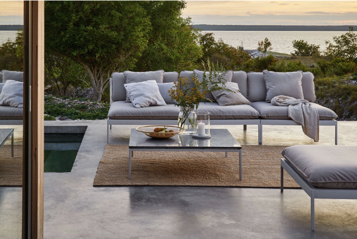 Terrasse med et loungesofa i aluminium. I midten står en utepeis. Vi har samlet årets hagemøbler for 2023.