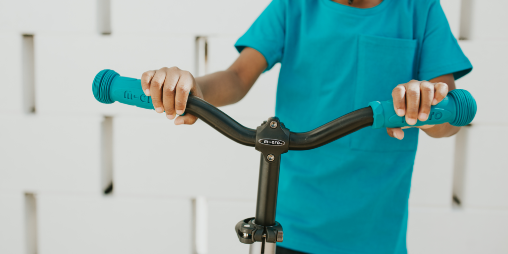 Sparkesykkel barn: Et barn holder i styret på en Micro-sparkesykkel.