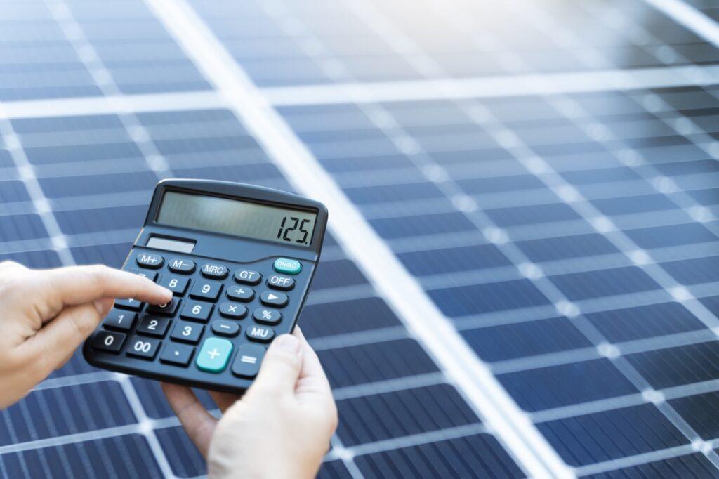 Solcellepanel lønnsomhet: Illustrasjonsbilde av person med kalkulator foran solpanel.