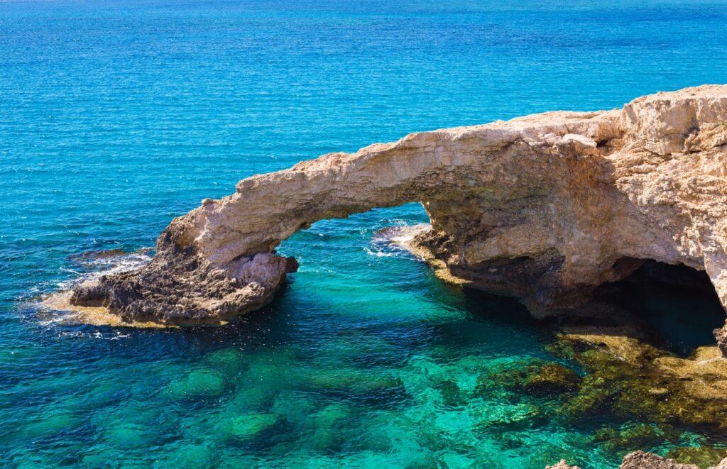 Berg med hull i omringet av krystallklart hav på Aya Napa på Kypros. Her finner du restplasser til Kypros slik at du kan nyte en billig sydenferie på den vakre middelhavsøya.