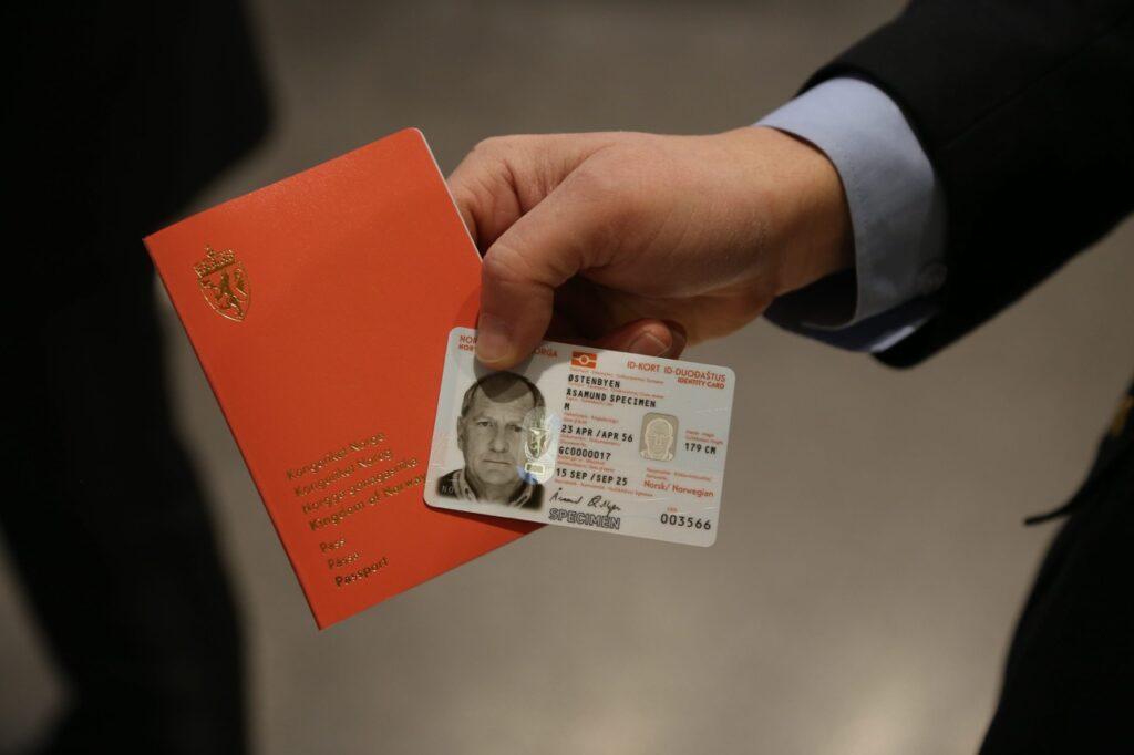 På bilde ser man en hånd som holder et norsk pass og ID-kort. Vi har snakket med Politidirektoratet for å finne ut hva forskjellene er på pass og nasjonalt id-kort, og hva man skal velge av de to.