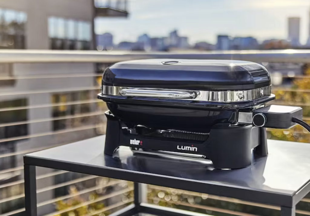 Bilde av best i test Weber Lumin Compact elektrisk bordgrill på en balkong.