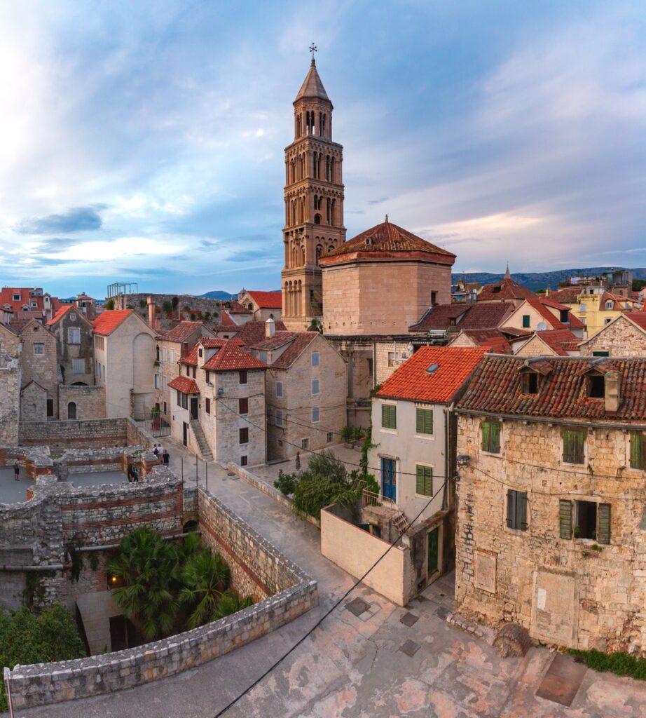 Bilde av gamlebyen, også kjent som Diokletians palass i Split, Kroatia. Her ser du gamle murbygg med røde tak, og i bakgrunnen sår katedralen St. Domnius. Vi gir deg 5 tips til ting du må se og oppleve i byen, tips til hvor du finner billige reiser, samt svar på ofte stilte spørsmål om Split.
