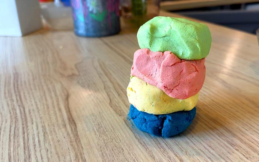 Fire ulike lekedeiger oppå hverandre, blå, gul, rosa og grønn. Her viser vi oppskriften på lekedeig med to ingredienser.