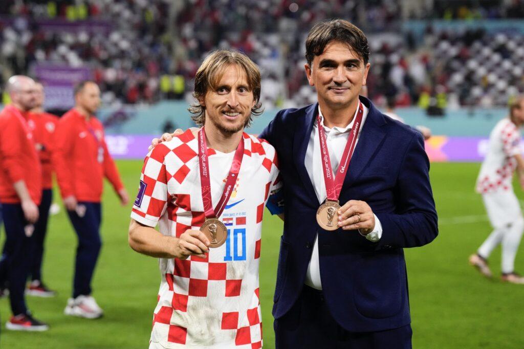 Kroatias landslagstrener Zlatko Dalic og spiller Luka Modric smilende, med bronsemedaljene rundt halsen etter seieren i bronsefinalen i VM 2022 i fotball.