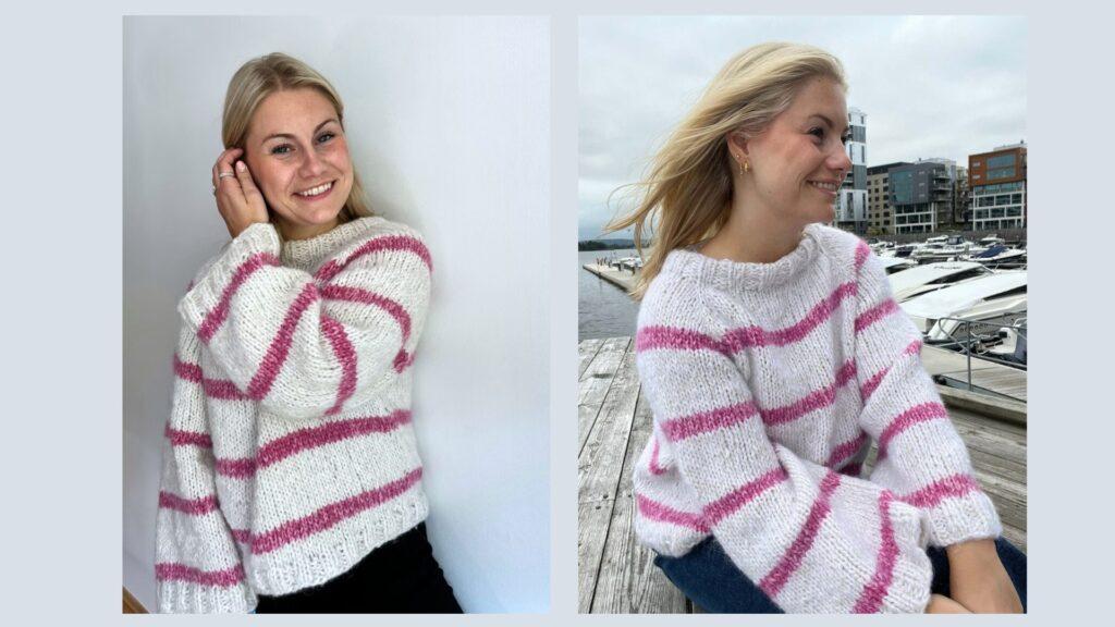 Emilie smiler mens hun poserer mot en hvit vegg iført Carolinegenseren, hennes eget strikkedesign. Genseren er håndstrikket i mykt garn med hvit base og delikate rosa striper. Den har en oversized passform, vide ermer og et lunt uttrykk som kombinerer stil og komfort.