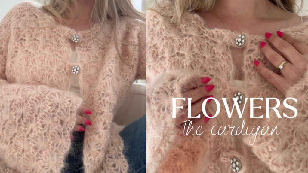 Nærbilde av en myk, rosa mohaircardigan fra Ull & Strikk’s Flowers-serie, båret over en hvit singlet. Cardiganen har et løst, hårete strikkmønster og en rund halsåpning. Den lukkes med tre store, blanke blomsterknapper dekket med klare krystallstein. To hender med knallrosa neglelakk og en guldring med én klar sten holder sammen forstykkene, og fremhever både tekstur og feminine detaljer i plagget.