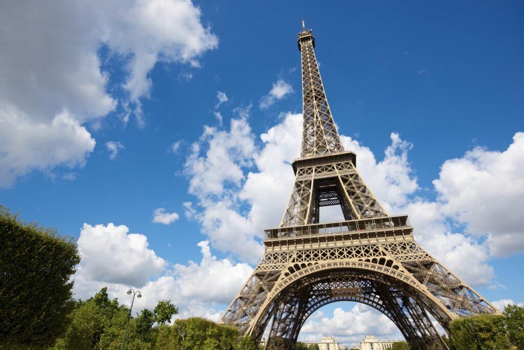 Bilde av Eiffeltårnet fra et froskeperspektiv hvor man ser opp på tårnet og en blå himmel. Vi gir deg en omfattende guide til kjærlighetens by som kan by på alt fra Triumfbuen, Louvre, Notre-Dame, Disneyland Paris og mye mer.