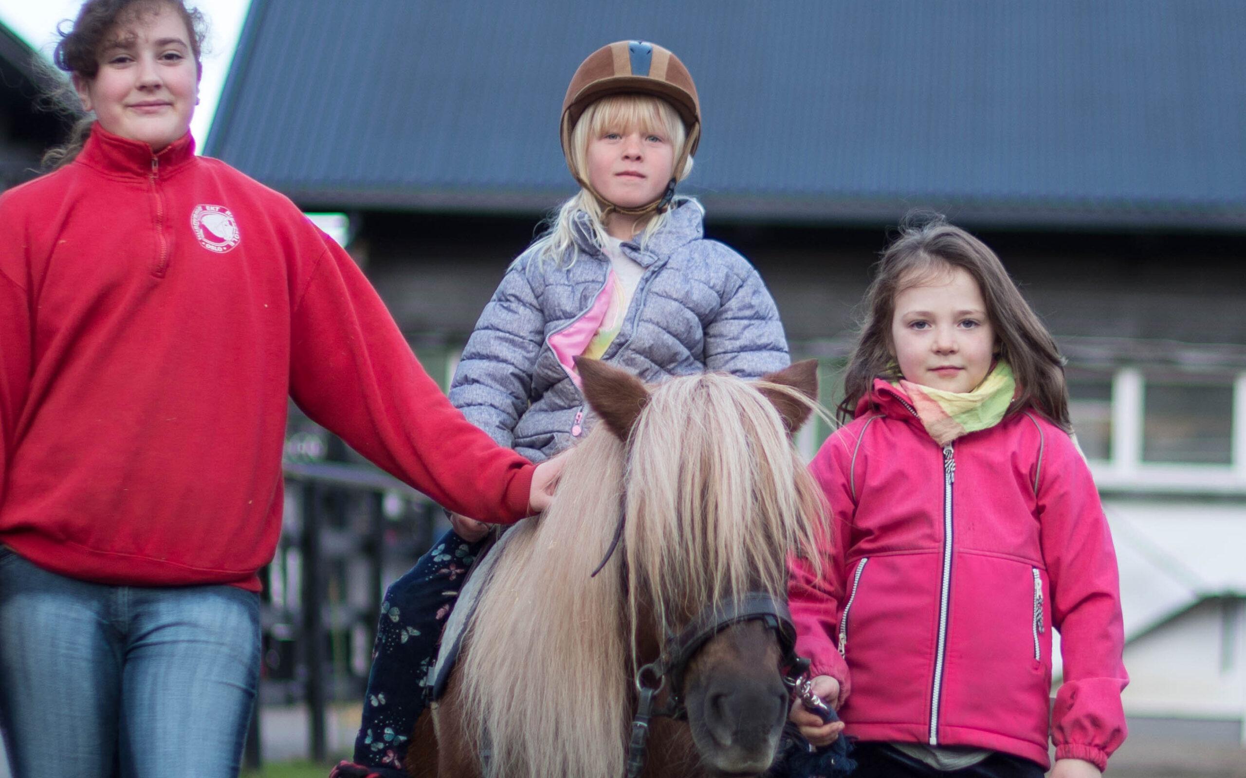 Jente på hesteryggen med venninne og rideskolelærer på EKT Rideskole og Husdyrpark på Ekeberg.