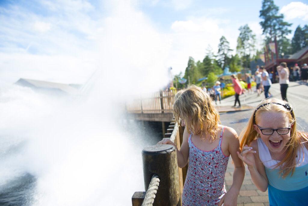 To jenter får vann sprutet over av berg og dalbanen SuperSplah hos Tusenfryd utenfor Oslo.