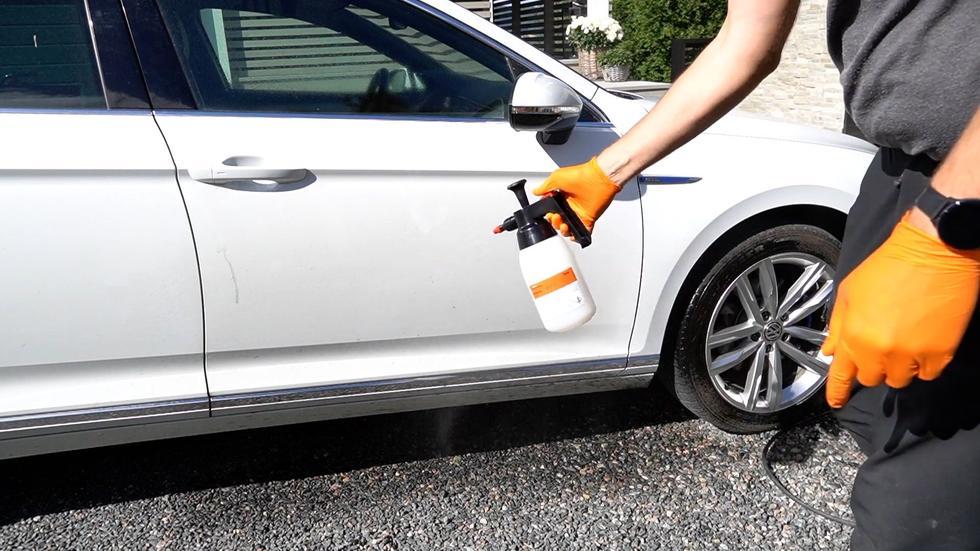 Person som er i gang med bilvask og skal til å ha såpe på bilen, hand mes sprayflaske med såpe