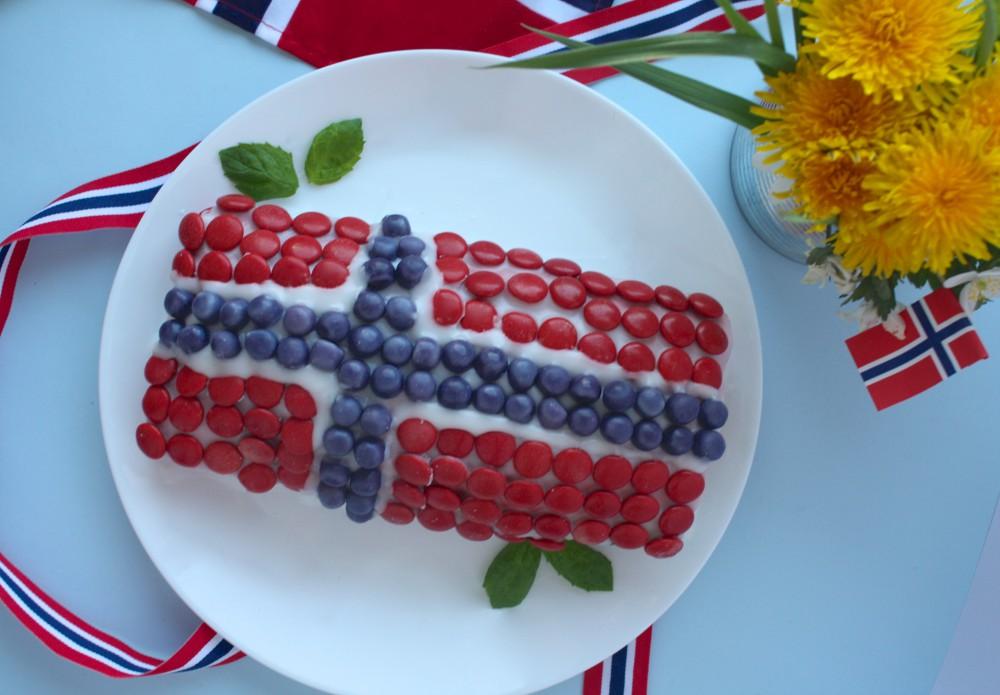 Bilde av kake på bord og tallerken i fargene rødt, hvitt og blått til 17. mai.