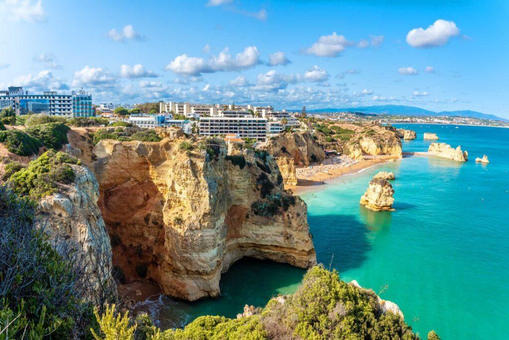 Bilde av bygg på toppen av klipper, med blått hav i sommersol under en sommerferie i Portugal.