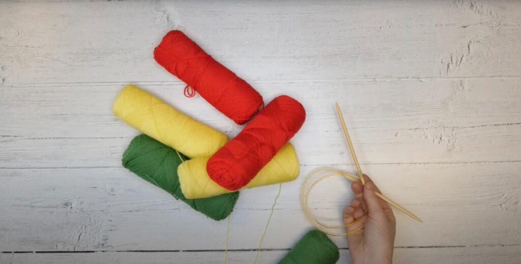 Kjøp rød, grønn og gult garn til denne strikkeoppskriften for å få Kvikk Lunsj fargene på sokkene, bilde va strikkepinner og garn. 