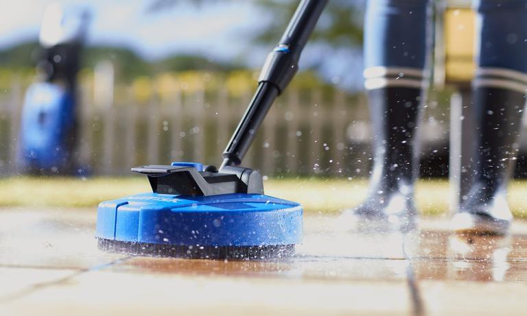 Person som bruker en blå terrassevasker på uteområdet for å vaske terrassen. Vi gir deg gode råd på hvordan du vedlikeholder terrassen på best mulig måte.