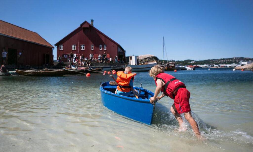 Bragdøya i kristiansand. to barn i en båt på stranda med ryggen til